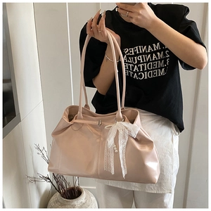 Detailed macro view of pink patent leather tote bag featuring lace bow and pearl charm