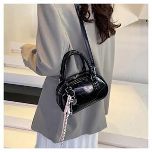 Glossy black bowling bag with decorative cord shown on model against white stairs