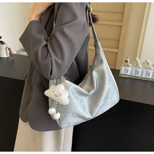 Silver metallic hobo bag with white cloud plush charm held by a model in a blazer