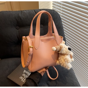 Pink lychee grain leather bucket bag with top handles and a cute puppy plush charm
