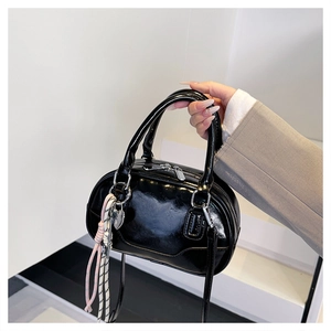 Close-up of glossy black leather bowling bag with double zipper and cute knot charm