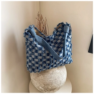 Close-up of blue and white checkered denim tote bag with frayed fringe edges