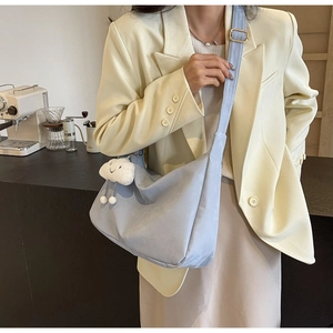 Macro detail of a soft light blue tote bag with a cute white plush cloud charm accessory