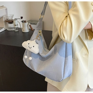 Close-up of light blue canvas tote bag with white cloud charm on a model in a cafe