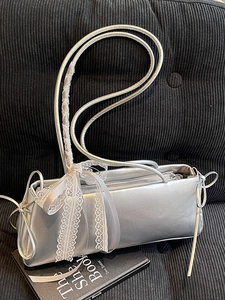 Silver metallic baguette shoulder bag with white lace bow on a black velvet background