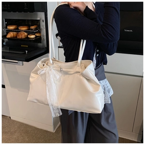 White glossy PU leather tote bag featuring a large lace bow detail on a shoulder strap