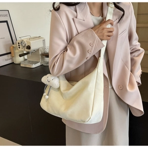 Detail of creamy white large tote bag featuring a cute cloud plush charm and adjustable strap