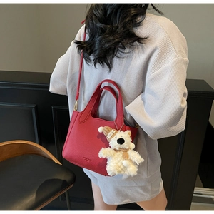 Detail of red lychee pattern leather tote bag with polar bear charm and embossed logo