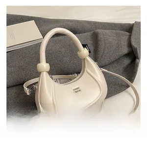 Dettaglio di una borsa hobo beige crema con decorazioni sferiche sul manico