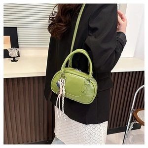 Detail of glossy grass green patent leather bowling bag with stylish charms on the side