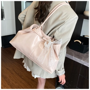 Detail of light pink tote bag featuring a white lace bow and pearl accents on the side
