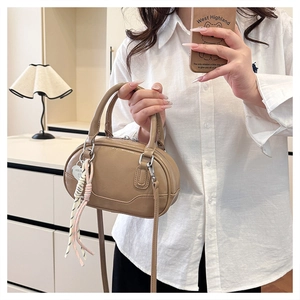 Detail of light brown bowling bag with heart pendant and colorful tassel decoration