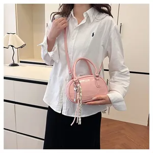 Detail view of pink patent leather bowling bag with decorative pendants and shoulder strap