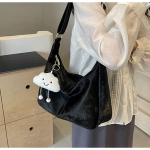 Detail of black velvet tote bag with white cloud plush charm and adjustable strap