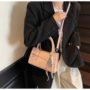Dettaglio borsa a tracolla rosa in ecopelle con fiocco elegante e ciondolo indossata da modella