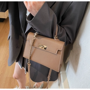 Crossbody shot of a tan Kelly style mini bag with gold twist lock and chain strap