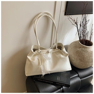 Detail of cream tote bag featuring a white lace bow and elegant pearl charm ornament