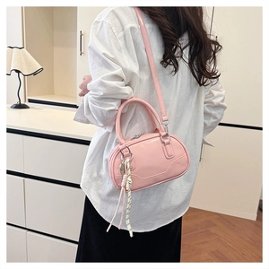 Detail view of pink bowling bag with top handle and woven rope pendant on shoulder