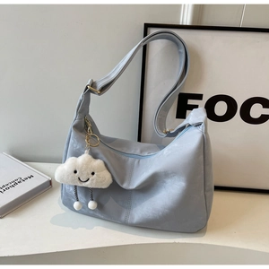 Close-up of light blue soft leather tote with cute white cloud plush pendant detail