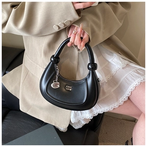 Dettaglio borsa hobo nera a mezzaluna con nodi a sfera e un ciondolo a cuore in metallo
