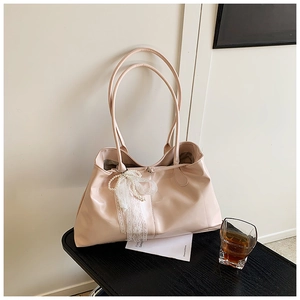 Detail of light pink glossy tote bag featuring white lace bow and elegant pearl charms