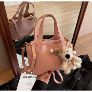Pink lychee grain leather bucket bag with top handles and a cute puppy plush charm