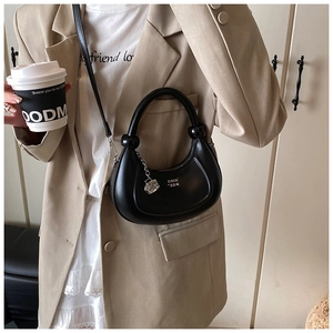 Dettaglio borsa a mezzaluna in finta pelle nera con ciondolo a cubetto di ghiaccio e tracolla
