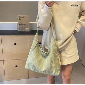 Close-up of sage green tote bag featuring wrinkled texture leather and simple hangtag