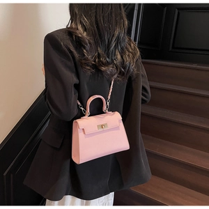 Pink textured leather Kelly bag with gold twist lock shown from rear view on model