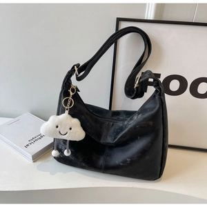 Detail shot of a black leather hobo bag with a cute white cloud plush charm