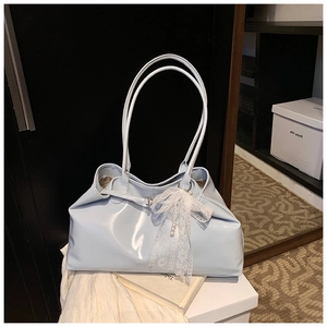 Detail of light blue patent leather tote bag with white lace bow and pearl pendant