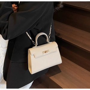 Detail of cream-white leather Kelly bag featuring golden clasp and metal chain strap