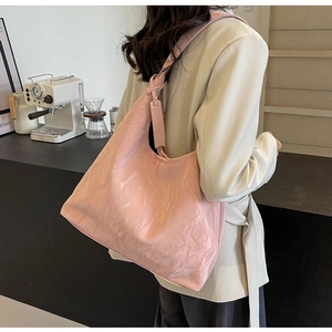 Detail of soft pale pink tote bag featuring knotted strap and smooth pleated texture