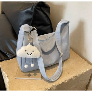 Detail of light blue soft leather hobo bag with white cloud plush charm on stone base