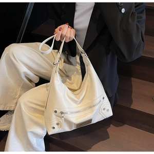 Détails d'un sac hobo blanc crème avec clous argentés et fermetures éclair en métal