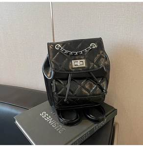 Detail of black quilted leather backpack with silver chain and twist lock closure