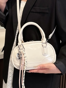 Minimalist white bowling bag with glossy finish and heart pendant charm detail