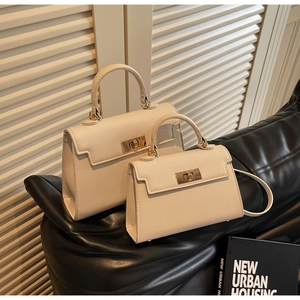Detail of cream leather Kelly bags in two sizes with elegant gold twist-lock hardware