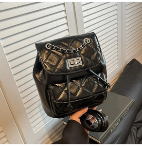 Detail of black quilted leather texture and silver metallic twist lock on the backpack