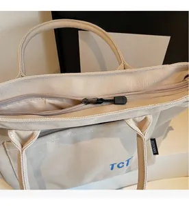 Detail of the smooth metal zipper closure on the beige canvas tote bag with TCT print