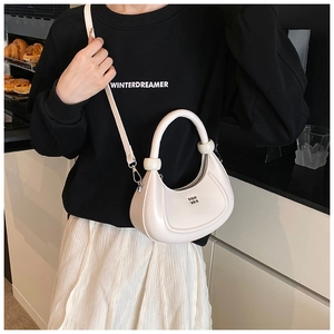 Dettaglio borsa a tracolla a mezzaluna bianco crema con texture in pelle e manico