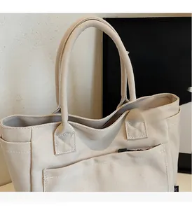 Close-up of beige canvas tote bag showing double handles and functional front pocket