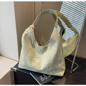 Macro shot of light green hobo bag with pleated texture and stylish brand hangtag