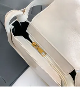 Detail of premium cream leather handbag featuring a smooth golden metal zipper slider