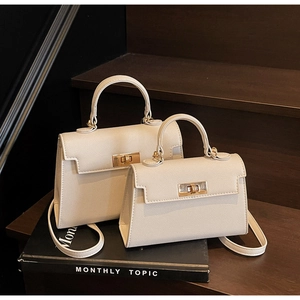 Detail of cream leather Kelly style handbags with lychee texture on dark wood steps