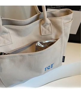 Detail of beige canvas tote bag showing thick texture and functional zipper pocket