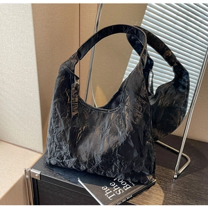 Close-up of black wrinkled leather texture on a spacious tote bag with wide shoulder strap