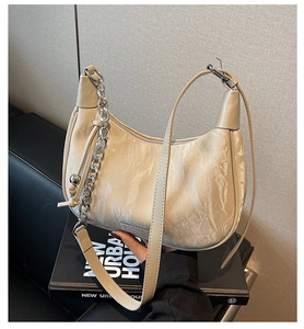 Détail du sac beige en cuir plissé avec une chaîne en métal argenté et bandoulière