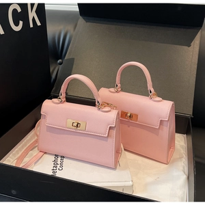 Detail view of pink leather handbag with gold metal hardware in a gift box packaging