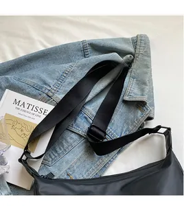Detail view of the black nylon messenger bag featuring an adjustable strap and matte buckle